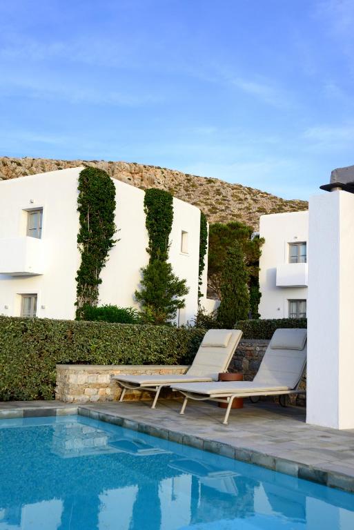 a pool with two lounge chairs next to a building at ANEMI Folegandros in Karavostasi