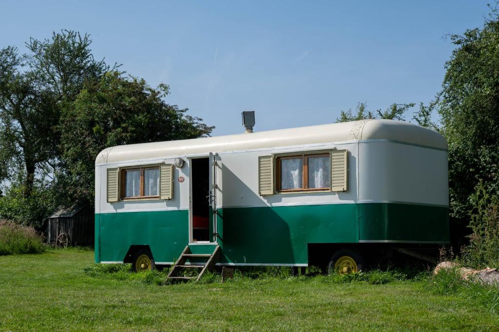 un rimorchio verde e bianco parcheggiato in un campo di Manoir du Bois Joly - Roulotte Vintage a Margon