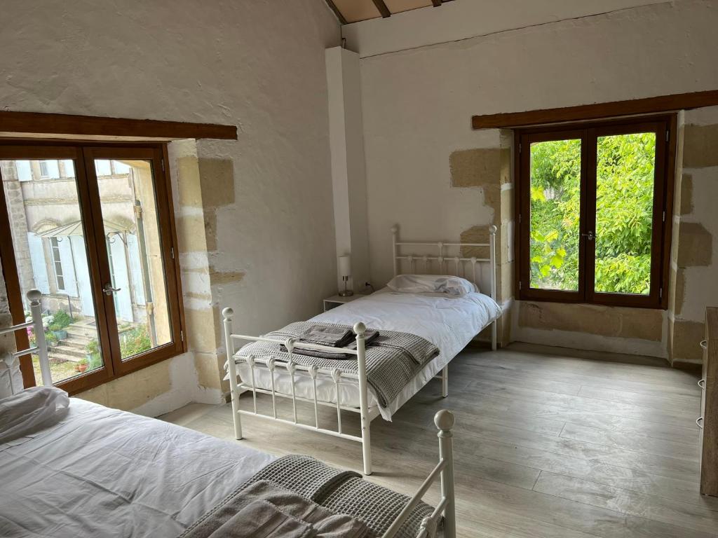 a bedroom with two beds and two windows at La Maison du Coeur Calme in Cancon