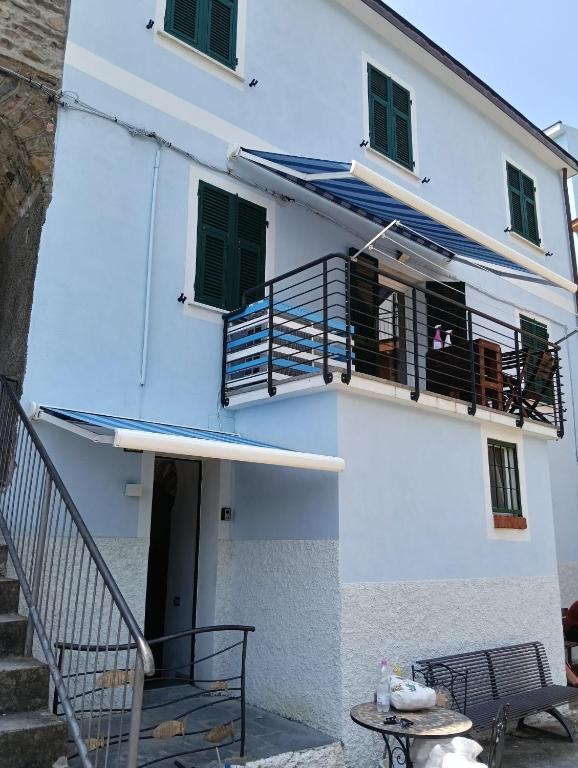 a white building with green shutters and a balcony at Affittacamere Il Timone in Corniglia