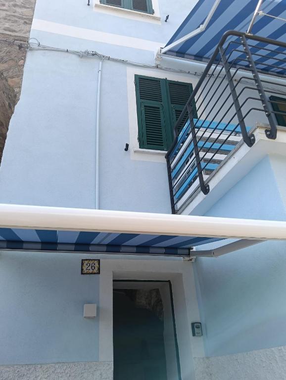 a white house with a blue awning and a staircase at Affittacamere Il Timone in Corniglia