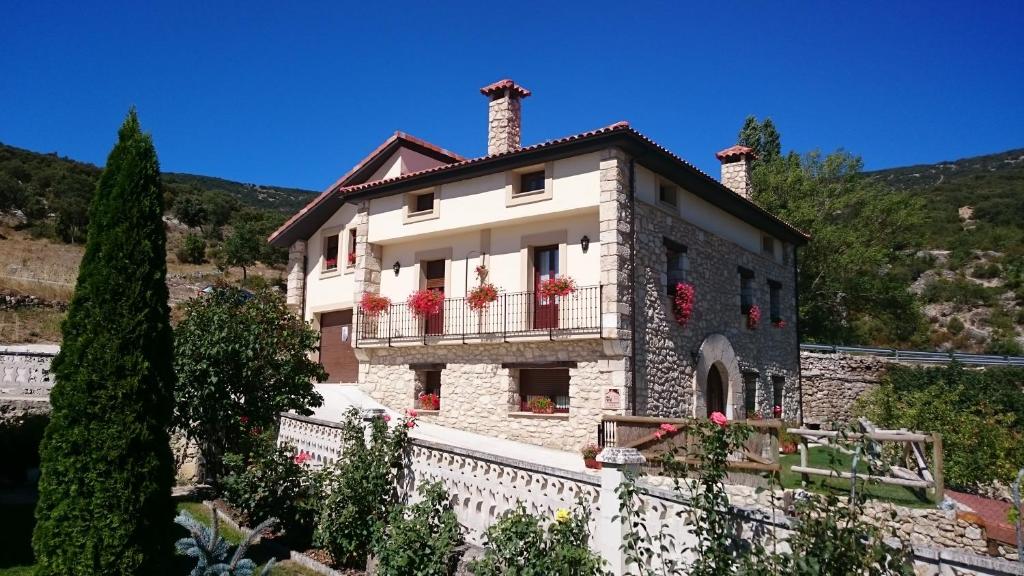 ein Haus auf einem Hügel mit Blumen auf dem Balkon in der Unterkunft Casa Rural Torres in Valdenoceda