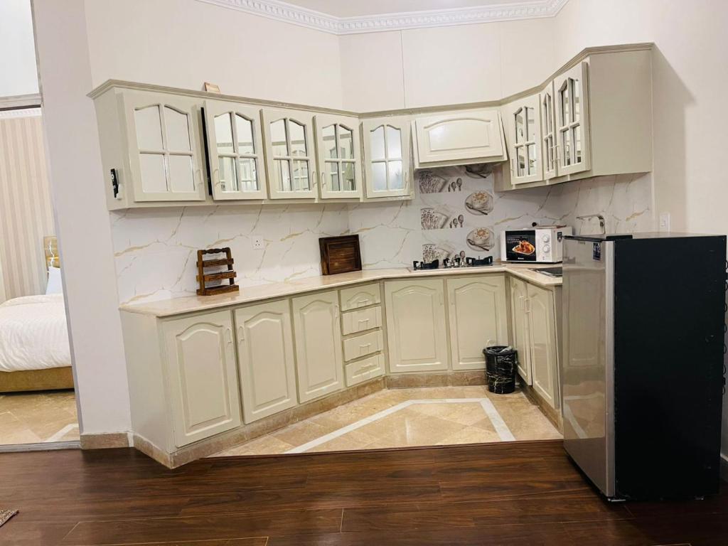 une cuisine avec des armoires blanches et un réfrigérateur noir dans l'établissement F-10 park tower, à Islamabad
