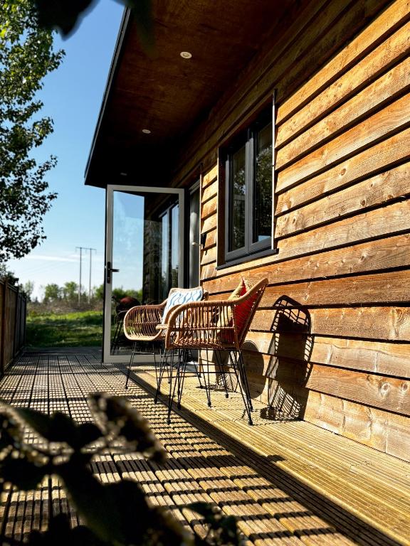 two chairs sitting on a porch of a house at Lakeside Lodge- 'Swallow' in Bishampton