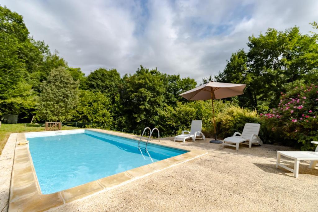 une piscine avec deux chaises et un parasol dans l'établissement Moulin de la Grenaderie, à Sergeac