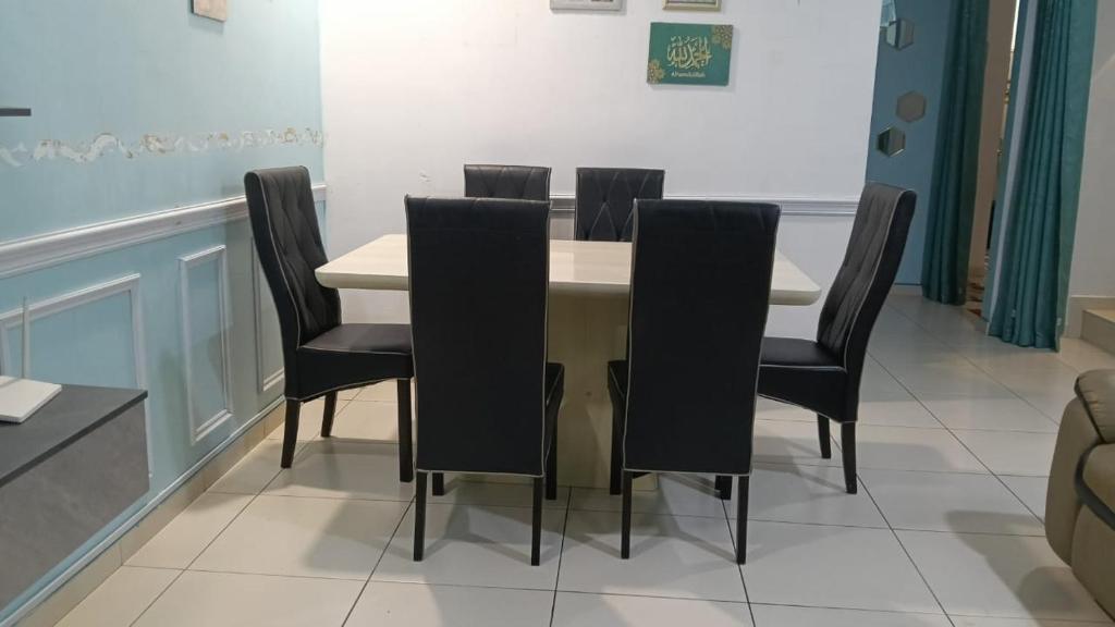 a dining room with a table and black chairs at Spacious 2-Storey Home in Kampong Alor