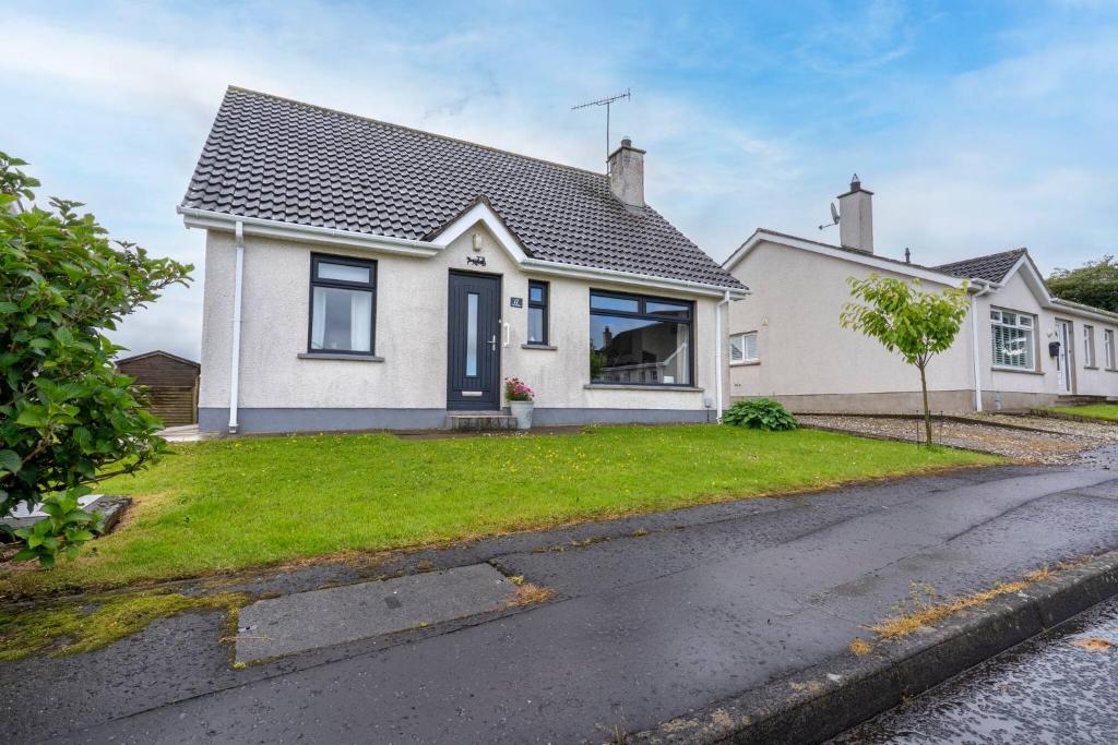 ein weißes Haus mit einem schwarzen Dach in der Unterkunft 3-Bed Portballintrae Home | Wi-Fi, Garden, Parking in Portballintrae