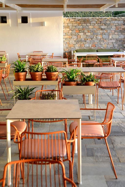an empty restaurant with tables and chairs and potted plants at ANEMI Folegandros in Karavostasi