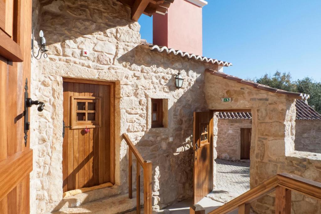 a stone house with wooden doors and a stairway at Casal Frias in Barreira
