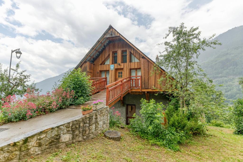 a large wooden house with a stone wall at Auberge Passoud 203 in Vaujany