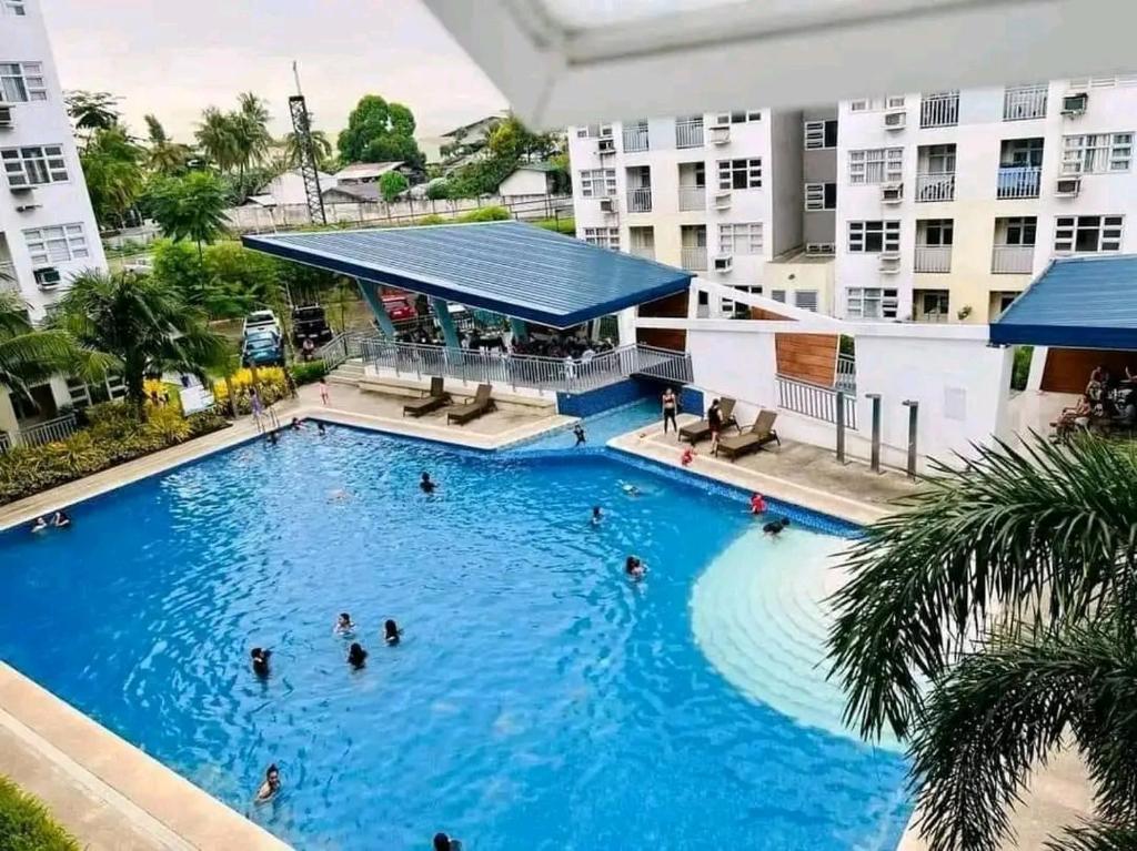 Una gran piscina con gente en ella frente a los edificios. en MC suites 2 Bedrooms condotel Staycation Davao City, Near davao airport SMX Sm lanang, Near Samal, Abreeza,Dusit, Azuela cove, sasa port, walking distance to sasa wharf, en Davao City