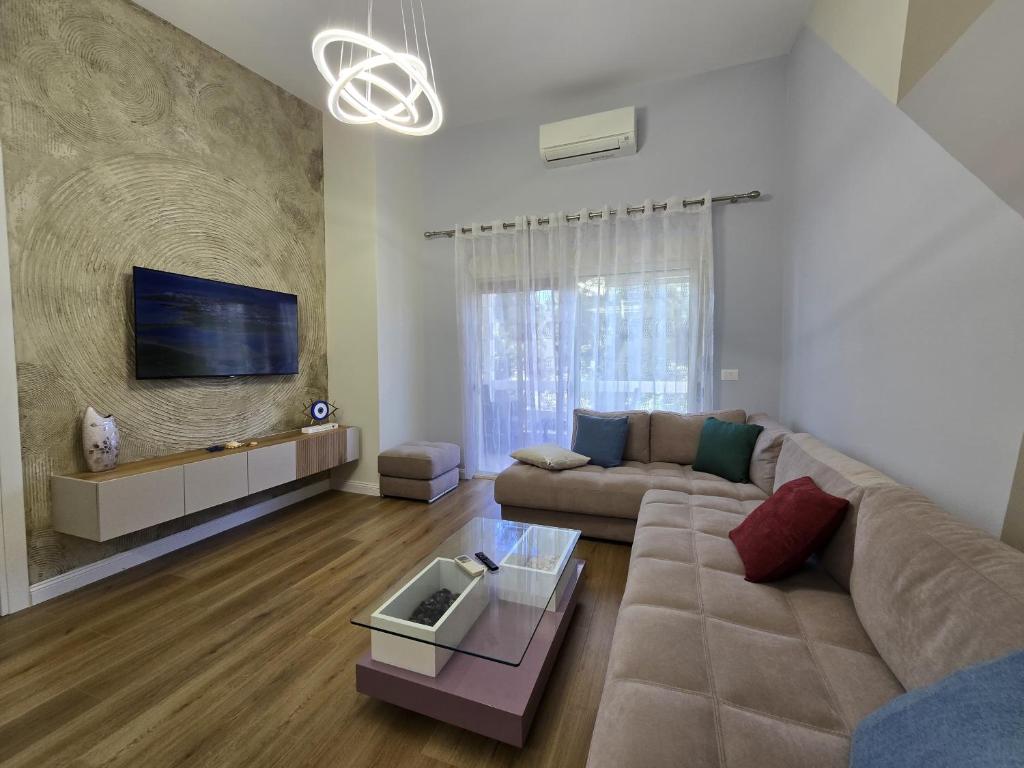 a living room with a couch and a tv at ApHEARTments in the Bay of Lalzi, Lura 1 in Mullini i Danit