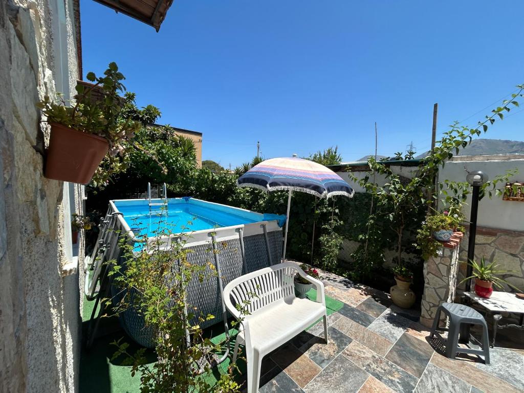 patio z krzesłem, parasolem i basenem w obiekcie Aromi di Sicilia Casa Vacanze w mieście Palermo