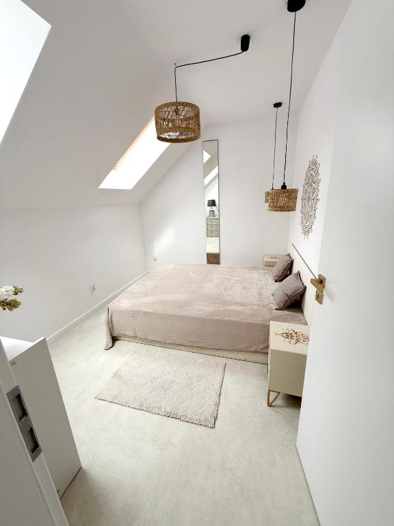 a white bedroom with a bed and a mirror at Apartament Szyszka in Rogowo