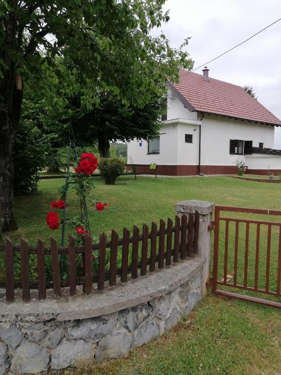 een hek voor een huis met rode bloemen bij Holiday Home Nada i Milan in Lovinac