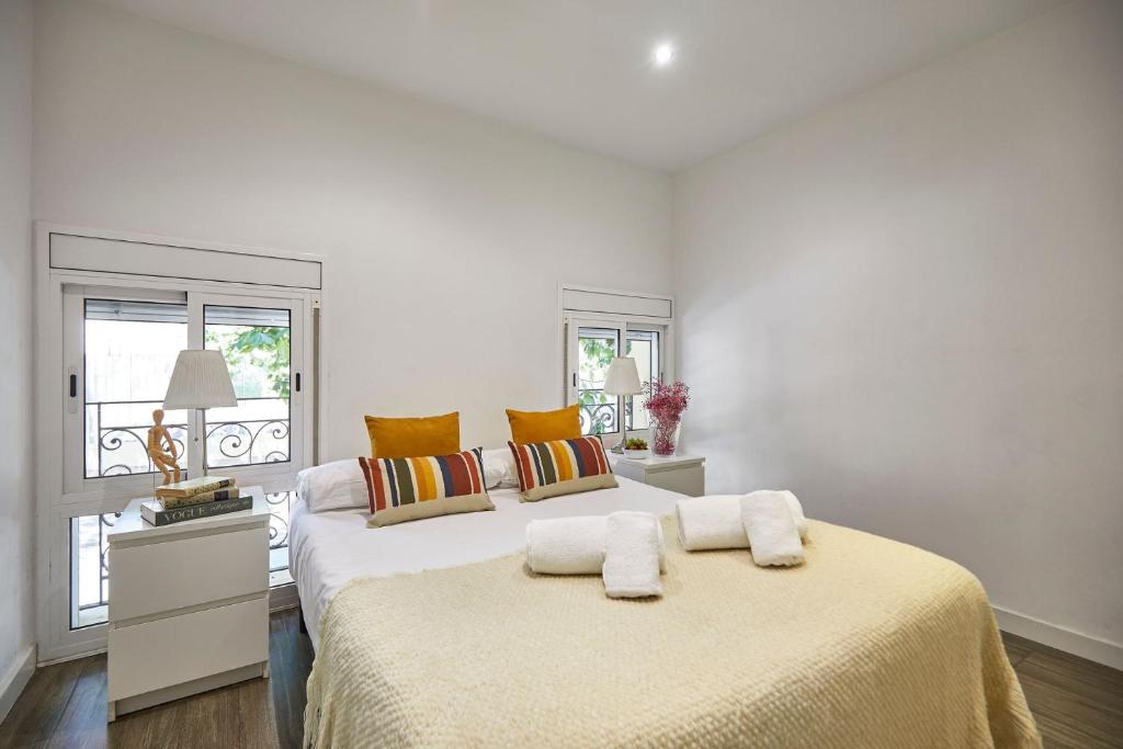 a white bedroom with a large bed with towels on it at BBarcelona Sant Pau Flat in Barcelona