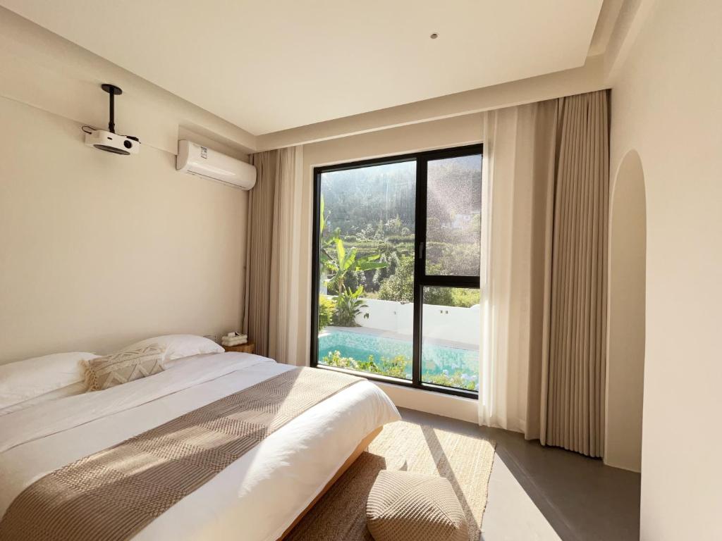 une chambre avec un lit et une grande fenêtre dans l'établissement 吾桐小院, à Zhangjiajie