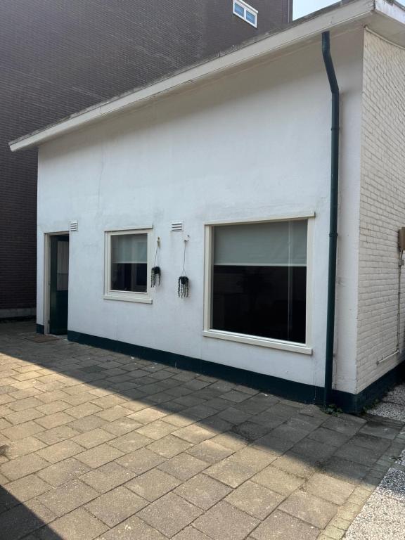 a white building with two windows on the side at Het zandhuisje 84 in Noordwijk aan Zee