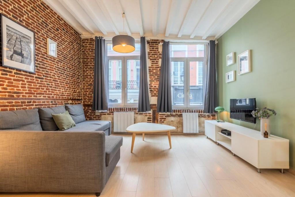 a living room with a couch and a brick wall at Old Town - Superb apartment in rue Esquermoise ! in Lille