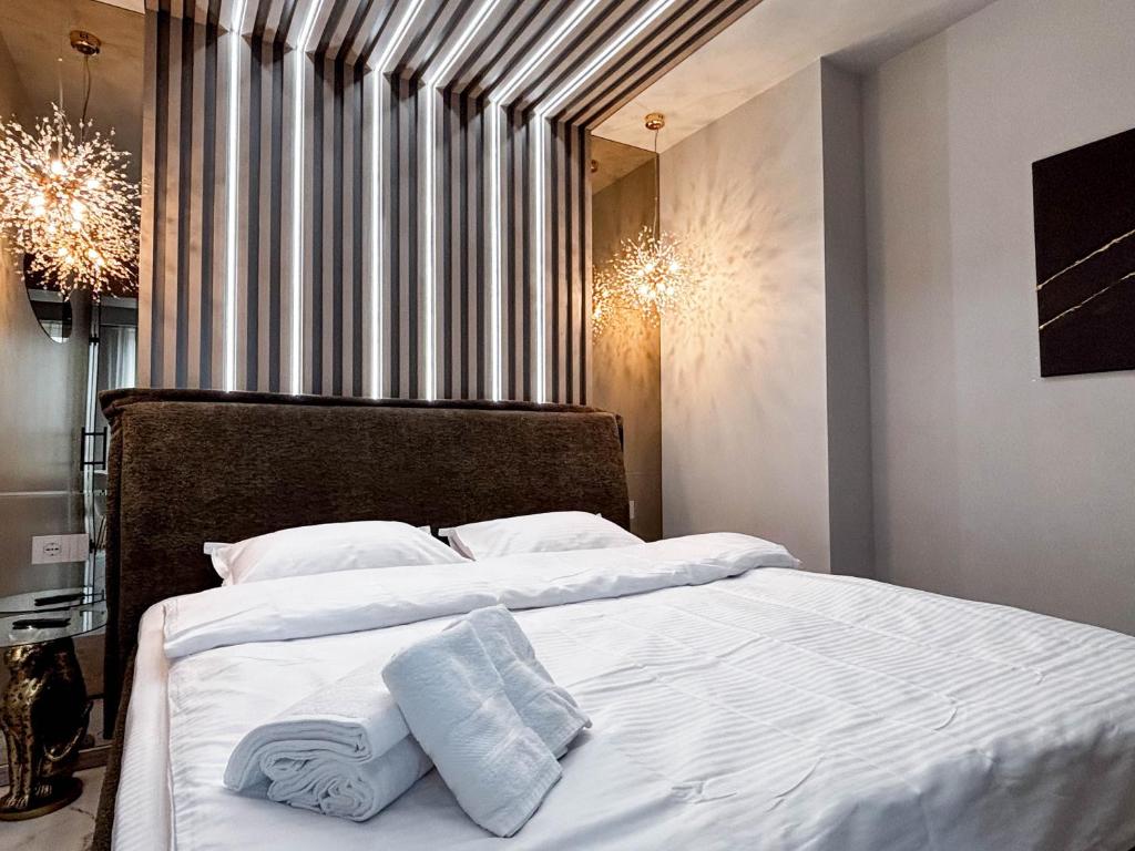 un dormitorio con una cama con sábanas y almohadas blancas en Airport SkyLuxe Luxury Residence, en Someşeni