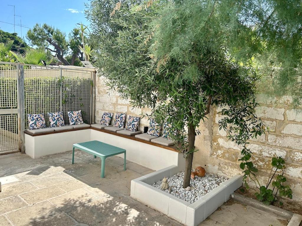 a bench with a tree sitting next to a wall at Casa Rosalia in Cozze