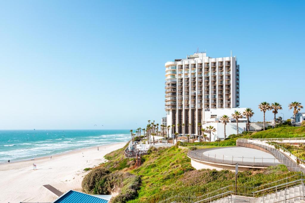 Blick auf den Strand, das Meer und ein Gebäude in der Unterkunft Daniel Herzliya Hotel in Herzlia
