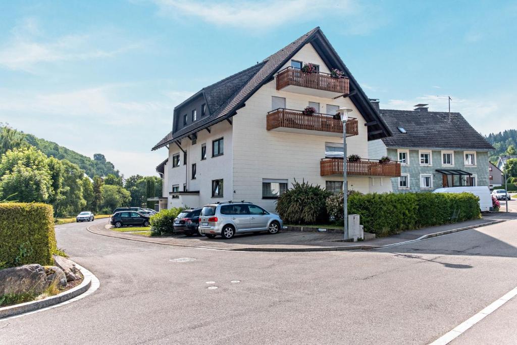 un grande edificio bianco con auto parcheggiate in un parcheggio di Gästehaus Schwörer a Lenzkirch