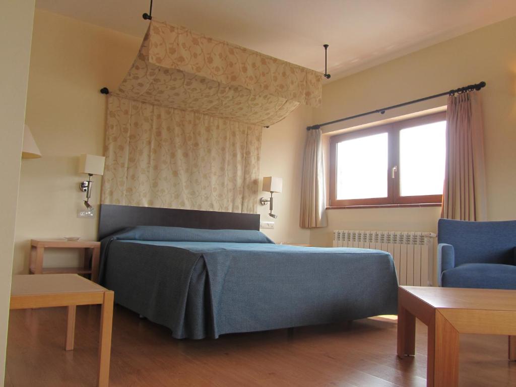 a bedroom with a blue bed and a window at Hotel Galayos in Hoyos del Espino