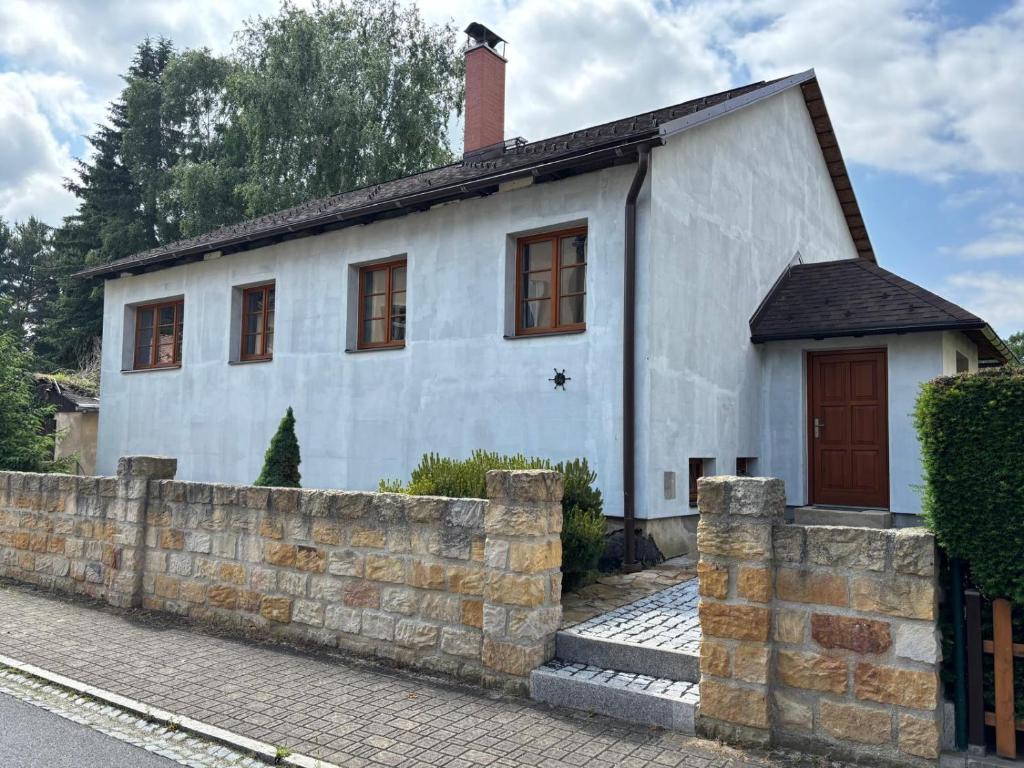 a small white house with a brick wall at Nicole in Hartau