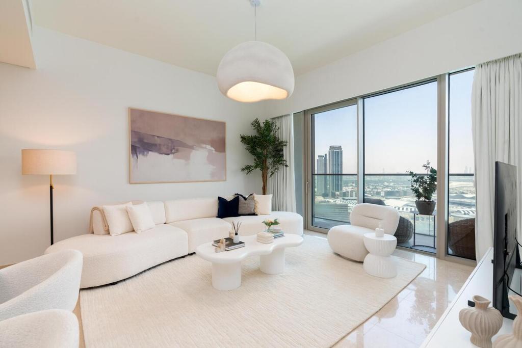 a living room with white furniture and a large window at Grande, Luxurious 2 BR, Burj Khalifa & Fountain view in Dubai