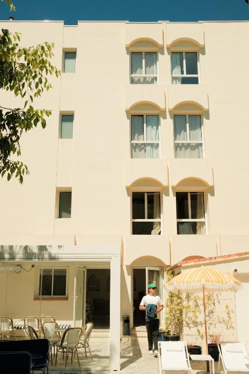 a man standing in front of a building at Hôtel Le Sud in Juan-les-Pins