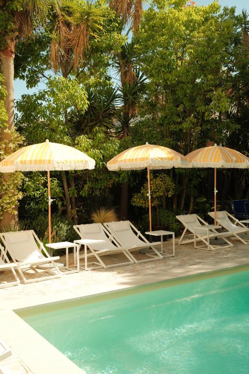 a group of chairs and umbrellas next to a pool at Hôtel Le Sud in Juan-les-Pins