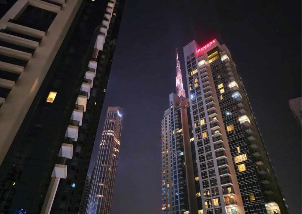 three tall buildings in a city at night at 2BR Luxury Suite with a Garden View in Dubai