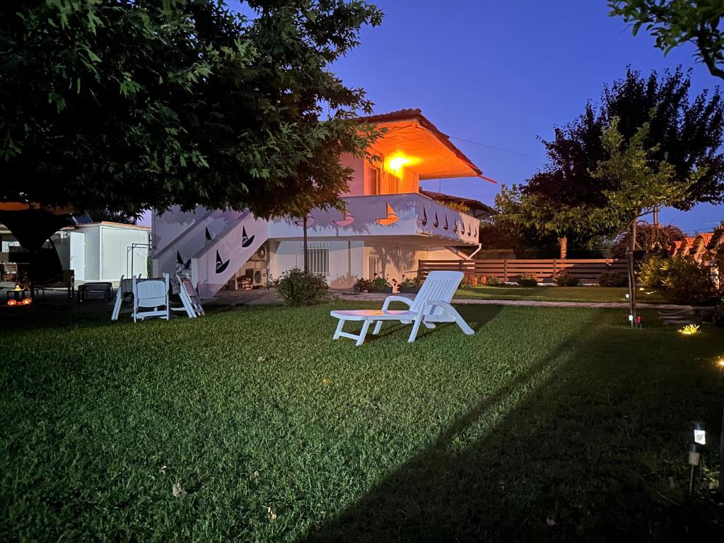 two white chairs sitting on a lawn in front of a house at Spacious seaside house in Nea Potidaea