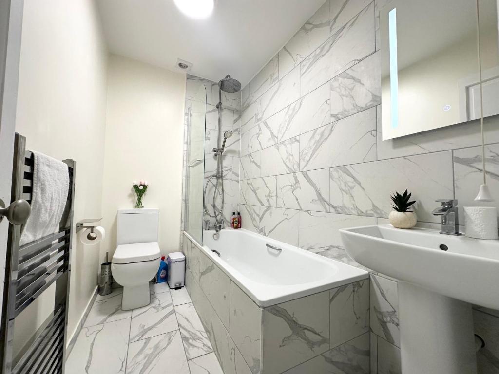 a white bathroom with a sink and a toilet at The Bournemouth Hideaway - Beautiful Central flat - 10 mins walk to beach - Brought to you by Coastline Retreats in Bournemouth