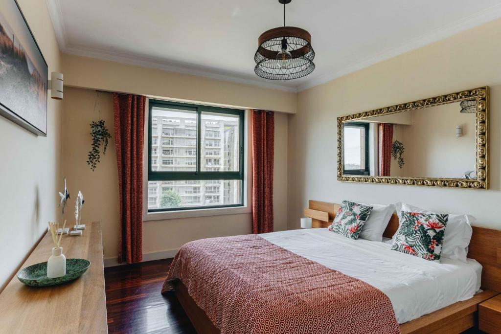 a bedroom with a large bed and a mirror at Spacious 1BR with Parking in Quiet Area in Vila Nova de Gaia
