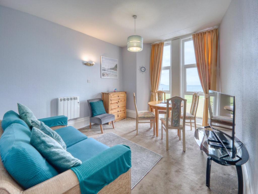 a living room with a blue couch and a table at Apartment 2 - 1 Bedroom Sea Front-Sea Views-Free Parking in Paignton