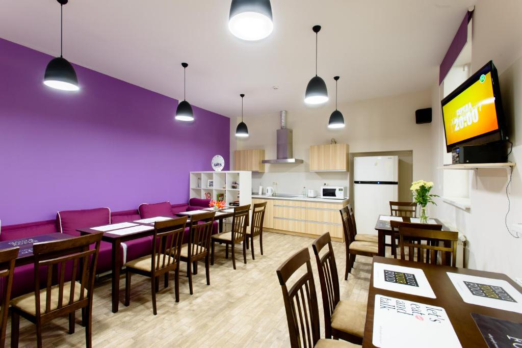 a restaurant with purple walls and wooden tables and chairs at Gar'is Hostel Lviv in Lviv