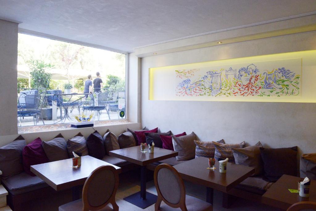 um restaurante com sofás e mesas e uma grande janela em Phidias Hotel by Oniro em Atenas