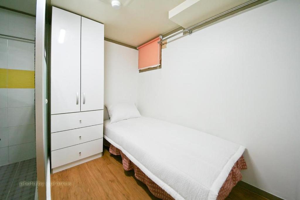 a small bedroom with a bed and a cabinet at Rodemhouse in Seoul