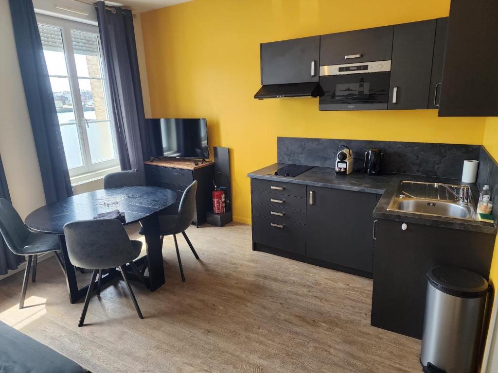 a kitchen with a table and chairs and a sink at La Rose Des Vents in Fécamp