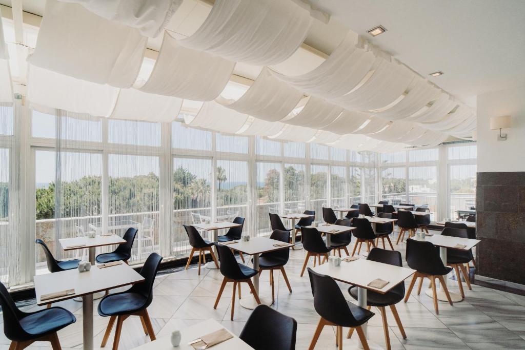 a dining room with tables and chairs and large windows at Velamar Boutique Hotel - Adults Friendly in Albufeira