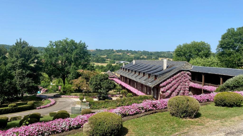 une maison avec des fleurs roses dans un jardin dans l'établissement Castel Novel Cottage, à Varetz
