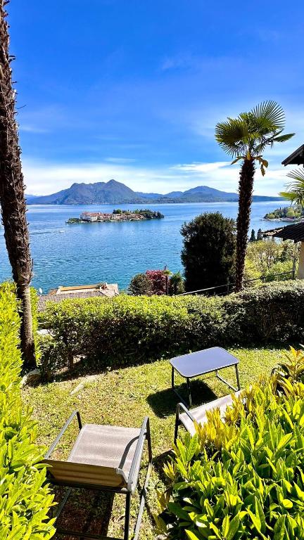 a table and chairs sitting on the grass near the water at Appartamento Marina in Stresa