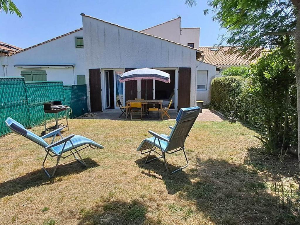 deux chaises et une table devant une maison dans l'établissement Maisonnette sécurisée avec piscine, tennis, Saint-Palais-sur-Mer - FR-1-550-94, à Saint-Palais-sur-Mer