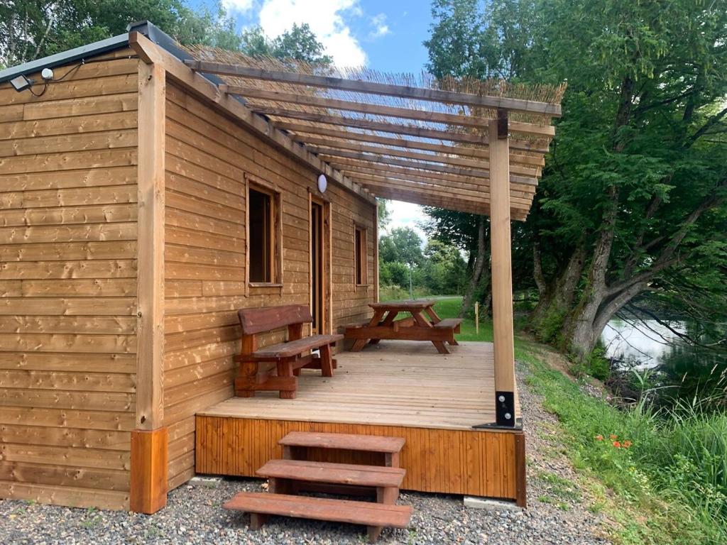 a wooden cabin with a picnic table and benches at La Ramure - Tiny chalet et sauna privatif, vue lac et pêche en famille in Roye