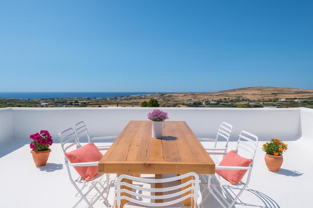 a wooden table and chairs on a balcony at Marouso Villa - Paros Seaview Getaway in Márpissa