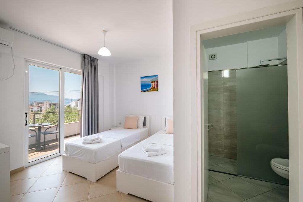 Una habitación blanca con un sofá y una ducha de cristal. en Sunshine Hotel, en Ksamil