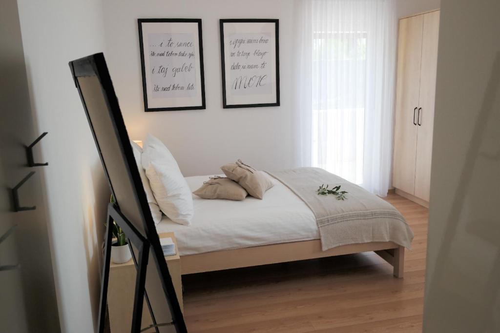 a bedroom with a bed with four pictures on the wall at KARBONACA APARTMENTS in Fažana