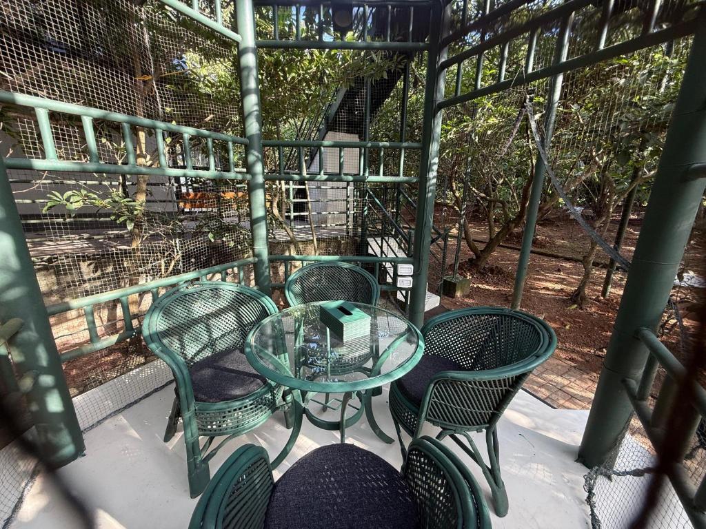 Una mesa de cristal y sillas en un balcón. en Farm House, en Kollam